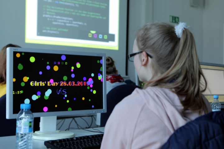 A girl, sitting infront of a computer screen, is coding her individual screen saver.